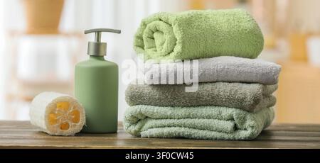 Stapel gefalteter Handtücher mit Seifenspender und Luffa Stockfoto
