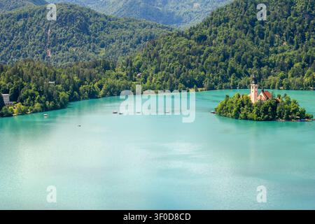Traditionelle Boote namens Pletna bringen Touristen und Pilger zur Kirche der Mariä Himmelfahrt auf der Insel Bled im Bledsee in Slowenien. Stockfoto