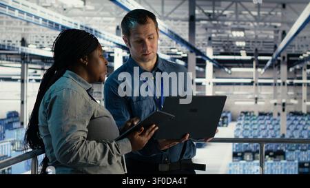 Das Engineering-Team des Rechenzentrums verwendet einen Laptop und ein Tablet in einem Serverraum, um die Testergebnisse zu überprüfen und den zuverlässigen Systembetrieb zu bestätigen. Stockfoto