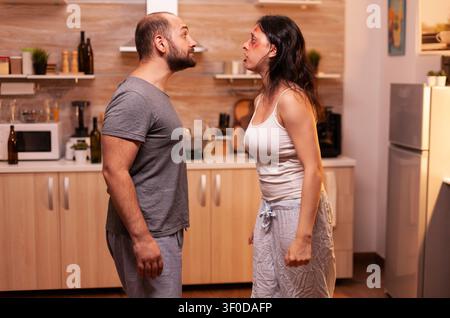 Weinende Ehefrau konfrontiert missbrauchenden Ehemann zu Hause, traumatisierte hilflose verängstigte verletzliche Ehefrau voller Blutergüsse mit Verletzungen. Stockfoto