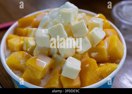 Koreanisches Mango-Bingsu-Dessert mit Käsekuchen-Würfeln und Kondensmilch Stockfoto