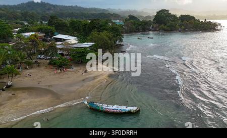 Luftbild zeigt den Strand von Puerto Viejo Talamanca, lokale Gebäude, Menschen, die sich entspannen, und ein mit Graffiti bedecktes Bootswrack im Karibischen Meer Stockfoto