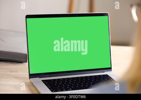 Grünes Mockup-Display auf dem Laptop-Monitor, Blick über die Schulter der Frau Stockfoto