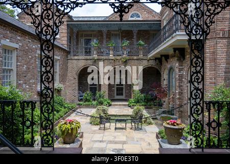 Blick durch kunstvolle schmiedeeiserne Tore in einen gepflegten Ziegelhof im Bellingrath-Haus in Theodore, Alabama, Vereinigte Staaten. Stockfoto