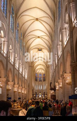Breite Innenansicht des Langhauses der Kathedrale Notre-Dame mit gewölbter Decke, Buntglas und Besuchern in Paris, Frankreich. Stockfoto