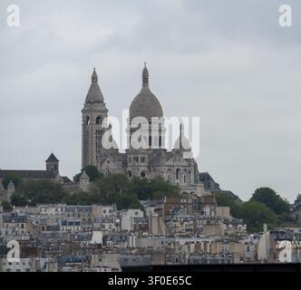 Teleobjektiv-Stadtbild der Sacré-Cœur-Basilika, die über den Dächern von Paris aufragt, gesehen vom Dach der Galeries Lafayette Haussmann. Stockfoto