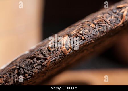 Nahaufnahme eines gepressten Pu-erh-Teekuchens, der die detaillierte Textur der getrockneten Teeblätter zeigt Stockfoto