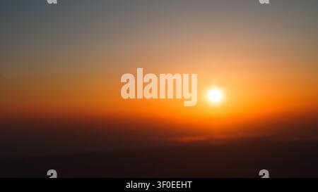 Neblige Bergkämme, die während eines goldenen Sonnenaufgangs von üppigen grünen Wäldern bedeckt sind Stockfoto