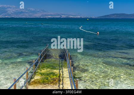 Eine Beton-Zufahrtsrampe mit Metallgeländern, die direkt ins Adriatische Meer führt und sicheren und bequemen Zugang für Rollstuhlfahrer und Menschen bietet Stockfoto