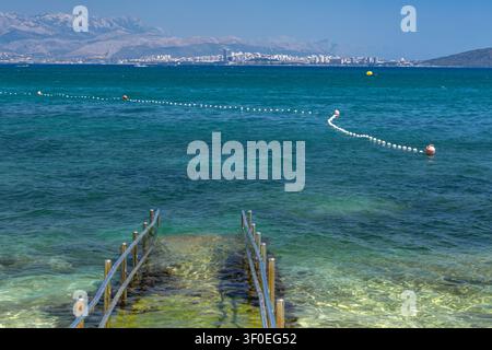 Eine Beton-Zufahrtsrampe mit Metallgeländern, die direkt ins Adriatische Meer führt und sicheren und bequemen Zugang für Rollstuhlfahrer und Menschen bietet Stockfoto