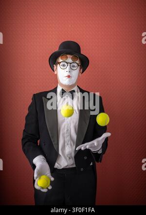 Männlicher Pantomime, der Tennisbälle jongliert Stockfoto