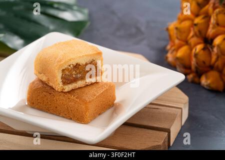 Traditionelles taiwanesisches Ananaskuchengebäck mit reichhaltiger Füllung und Ananas im Hintergrund. Stockfoto