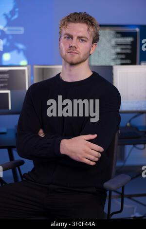 Männlicher Profi arbeitet in einem sicheren Operationszentrum mit Technologiemonitoren Stockfoto