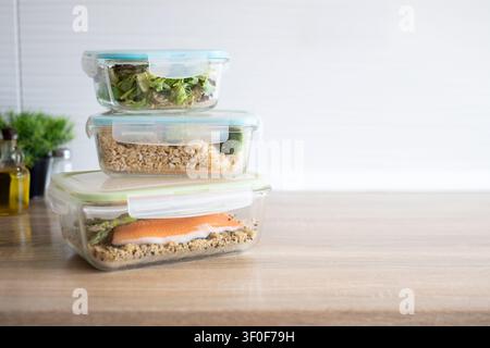 Stapel von gläsernen Meal-Prep-Behältern, gefüllt mit gesunden hausgemachten Mittagessen auf einem Holztisch. Stockfoto