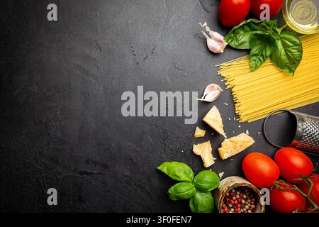 Hintergrund Pasta. Verschiedene Arten von trockener Pasta mit Gemüse und Kräutern auf schwarzem Hintergrund. Freier Platz für Text. Draufsicht Stockfoto