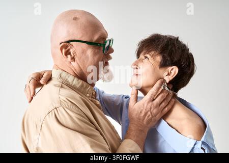 Ein liebevolles Seniorenpaar posiert zusammen in stilvoller Kleidung und strahlt Wärme und Zuneigung aus. Stockfoto
