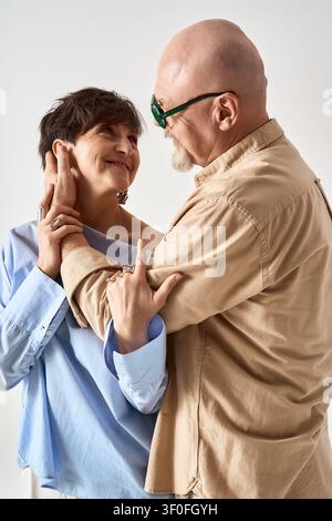 Ein fröhliches Seniorenehepaar teilt einen liebevollen Blick, während es stilvoll gekleidet ist und Wärme und Zuneigung ausstrahlt. Stockfoto