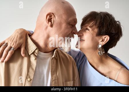Ein liebevolles Seniorenpaar teilt einen freudigen Moment in stilvollen Outfits und umarmt sich. Stockfoto