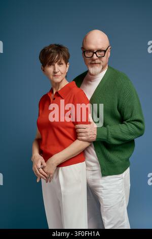 Älteres Paar steht eng beieinander und strahlt Zuneigung und Charme aus, während sie modische Outfits tragen. Stockfoto