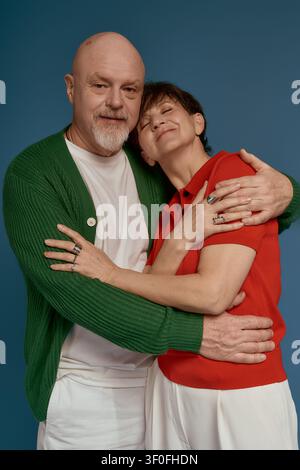 Ein warmes und charmantes Seniorenehepaar teilt eine liebevolle Umarmung, während sie modische Kleidung tragen. Stockfoto