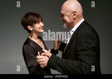 Ein liebevolles Seniorenpaar in eleganten Outfits teilt einen freudigen, zarten Moment miteinander. Stockfoto