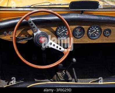 Azzida, Italien. Juli, 6. 2024. Fiat-Logo auf Holzlenkrad und Holzarmaturenbrett eines klassischen Spider der Sechzigerjahre während eines Oldtimerallyes. Stockfoto