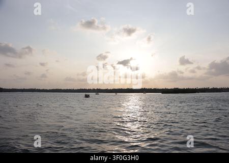 Wunderschöner Sonnenuntergang über dem Ashtamudi-See in Sambranikodi, Kollam, Kerala, mit goldenen Spiegelungen auf den ruhigen Backwaters und einem farbenfrohen Abendhimmel. Stockfoto
