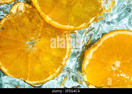 Oberansicht von frischen Orangenscheiben, die in klarem, welligem Wasser schwimmen Stockfoto
