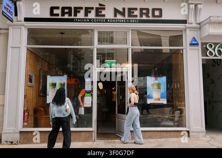 Fußgänger passieren die Schaufensterfront eines Caffè Nero-Kaffeehauses auf einer Straße im Stadtzentrum von Birmingham, UK Stockfoto