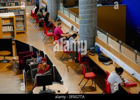 Hohe Blickwinkelansicht von Menschen und Studenten, die Laptops benutzen und in der Bibliothek von Birmingham, UK, lesen Stockfoto