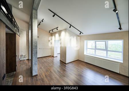 Geräumiger moderner Raum mit großem Fenster, Heizkörper und schwarzen Strahler, weite Aussicht auf leere Doppelhaushälfte innen. Zeitgenössisches Wohndesign, Renovierung und Immobilienkonzept Stockfoto