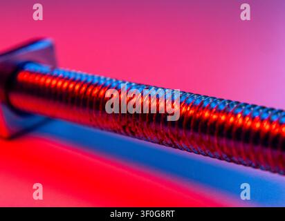 Metallverschluss mit detaillierter Gewindeverläufung und Reflexion, beleuchtet in kräftiger Farbe, Nahaufnahme Stockfoto