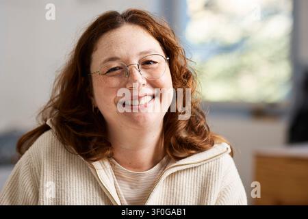 Lächelnde rothaarige Studiobesitzerin für Töpferwaren und kreative Künstlerin im Arbeitsbereich Stockfoto
