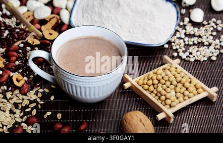 Verschiedene Getreidesorten, Bohnen und Mehlpulver auf einer dunklen Bambusmatte Stockfoto