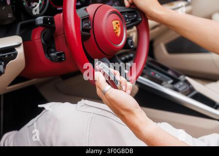 Ljubljana, Slowenien - 2. Juni 2026: Eine Hand hält den Schlüssel eines Porsche 911 Targa 4S im Inneren des Autos mit modernem Design und hellen Farben. Stockfoto