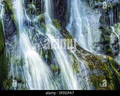 Detail von strömendem Wasser, das über moosige Felsen im Powerscourt-Wasserfall in der Grafschaft Wicklow in Irland stürzt. Stockfoto