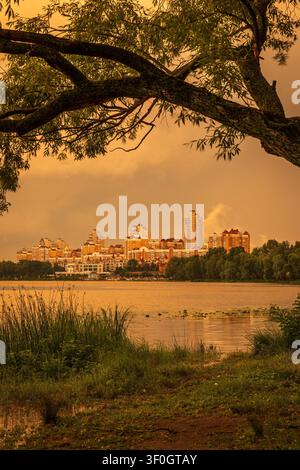 Dramatischer Sonnenuntergang nach einem Gewitter über der Obolon-Terrasse in Kiew, Ukraine. Sonnenlicht bricht durch Gewitterwolken und spiegelt sich im Dnipro-Fluss wider Stockfoto