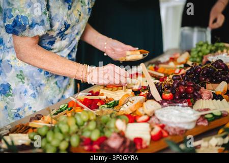 Frau, die Essen von einem großen Buffettisch bei einer Feier nimmt Stockfoto