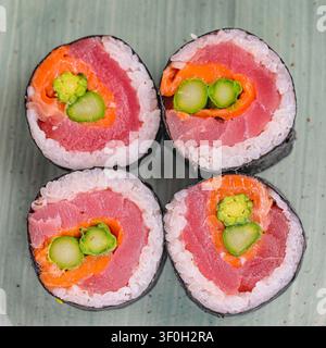 Ein Foto mit vier Sushi-Rollen, auf denen frische Gurkenscheiben platziert sind. Stockfoto