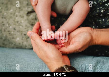 Vater hält kleine Neugeborenenzfüße in seinen Händen Stockfoto