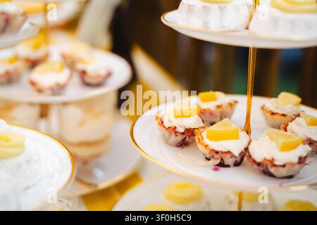 Verschiedene mundgerechte Desserts auf gestuften Servierständern mit goldenen Rändern Stockfoto