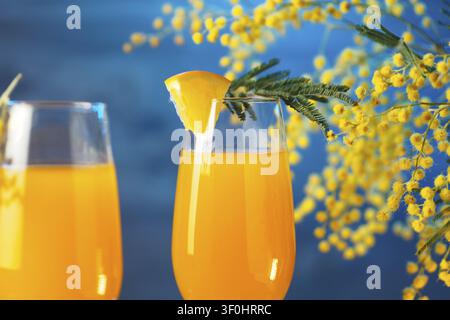 Cocktail Mimosa und Blumen auf blauem Hintergrund Stockfoto