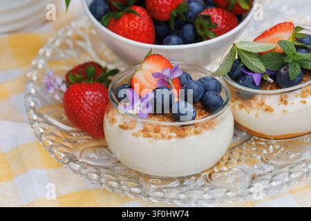 Nahaufnahme von Beeren-Käsekuchen-Tassen mit frischen Erdbeeren und Blaubeeren Stockfoto