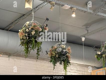 Hängende Blumenarrangements in einer modernen Inneneinrichtung mit industrieller Decke und Beleuchtung. Mobiles Foto Stockfoto