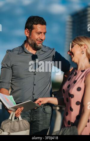 Mittelalterliches Paar lächelt, während es eine Karte während eines sonnigen Stadtspaziergangs überprüft Stockfoto