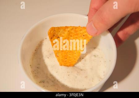 Knusprige gewürzte Tortilla-Maischips mit Salsasoße auf weißem Hintergrund im Detail Stockfoto