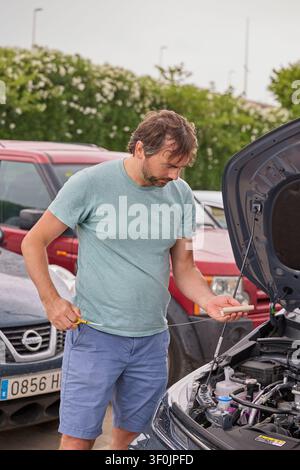 Mann überprüft den Motorölstand in einem Hybridauto während der routinemäßigen Wartungsinspektion. Stockfoto