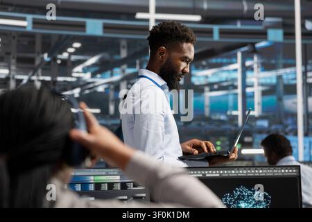 Serverraum-Spezialist arbeitet mit KI-Tieflernungsmodellen auf dem Laptop, um umfangreiche Datensätze zu überprüfen. Stockfoto