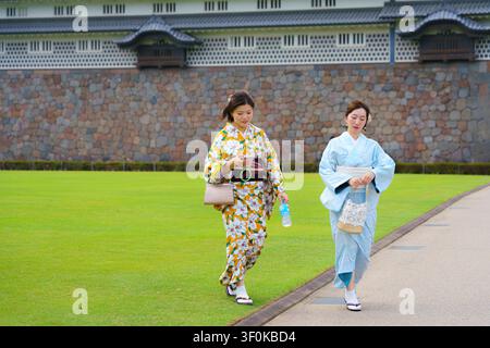 Kanazawa, Japan - 6. Okt 2024, Panoramablick auf zwei Mädchen in traditionellen Aimono-Kostümen, die auf einer Wiese durch den Innenhof von Kanazawa schlendern Stockfoto