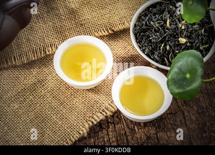 Traditioneller chinesischer grüner Tee, serviert in weißen Keramikbechern auf einem rustikalen Holztisch Stockfoto